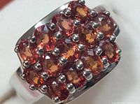 Close-up view of the ring face showing 15 oval orange sapphire stones arranged in three rows with white silver prong settings.