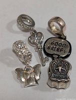 Four silver Pandora style charms with detailed engravings and rhinestones, shown on a plain background.