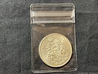 Reverse side of 1963 Canadian 50-cent coin showing Canadian Coat of Arms in clear protective sleeve.