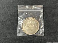 Coin showing reverse side with Voyageur design, canoe, fur trader, Indigenous guide, and date 1966.