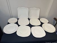 Full set of 10 antique Wedgwood Edme creamware plates in various oval, round, and square shapes, displayed on a dark cloth.