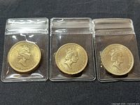 Three 1986 UK £2 commemorative coins in protective sleeves showing the obverse side with Queen Elizabeth II's portrait.