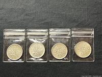 Four French 5 Franc .835 fine silver coins dated 1961 and 1963 with reverse showing the intermingled sprigs of wheat, oak, and olive, in plastic sleeves.