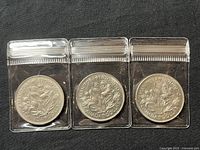 Three 1970 Canada Manitoba Centennial silver dollar coins in protective sleeves, displayed on black background.