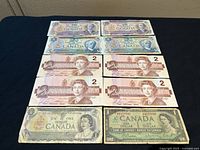 Banknotes arranged on black surface showing all denominations and dates