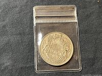 Photo of reverse side of 1949 Canadian 50 cent coin showing Canadian Coat of Arms design in detail.