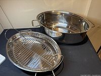 Oval stainless steel roasting pan, interior insert pan, and removable roasting rack displayed on table