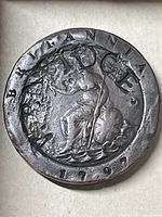 Close-up photo of the reverse side of the 1797 British Cartwheel Penny coin showing seated Britannia design, trident, shield, date, and circular inscription with some unusual stamped marks.