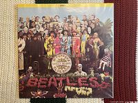 Front cover of the vibrant Sgt. Pepper’s Lonely Hearts Club Band gatefold album with The Beatles in colorful costumes surrounded by famous figures and floral text logo.