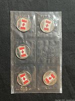 Set of five 2015 Canadian 25 cent coins with colored Canadian flag in sealed individual pockets.