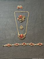 Full view of the complete Coro Victorian Revival style jewelry set including earrings, necklace, brooch, pendant, and bracelet on black background.