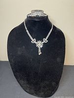 Front view of the necklace and bracelet displayed on black velvet stand showing sparkling clear rhinestones and clasp details.