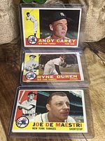 Photo of Andy Carey, Ryne Duren, and Joe De Maestri 1960 Topps New York Yankees baseball cards in plastic sleeves, showing front faces with player portraits and action shots.