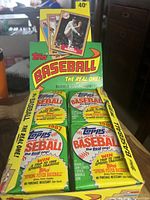 Four sealed packs of 1987 Topps baseball cards in their original display box, showing the front labeling and promotional card.