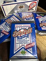 Four unopened 1991 Upper Deck baseball card packs on a wooden surface with box in the background.
