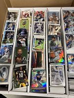 Five-compartment box filled with loose cards showing MLB and NFL player cards