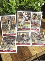 Photo showing the 6 Bryce Harper baseball cards in clear sleeves, standing upright in a natural outdoor setting