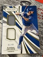 Front of the card showing Randal Grichuk in batting pose, with two game-used jersey swatches, serial numbered 1/49.