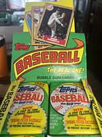 Four 1987 Topps Major League Baseball bubble gum card packs inside a partially full original box. Packs show promotional spring training trip text and classic 1987 Topps logo. Cards preview include pitcher Dave Righetti.