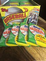 Four unopened 1987 Topps Baseball card packs displayed alongside the original box, showing front artwork with logo, baseball, and player images.