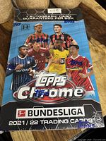 Front of sealed 2021-22 Topps Chrome Bundesliga soccer trading card hobby box showing players and autograph guarantee.