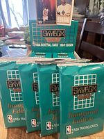 Four unopened packs of 1990-91 SkyBox NBA Basketball Cards stacked upright on a table.