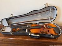 Open case showing violin and two bows