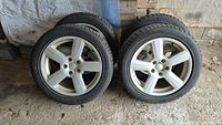 Four winter tires mounted on silver five-spoke Audi alloy rims arranged in two pairs