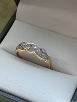 Ring placed inside a presentation box at an angle, showing the twisted design and diamond setting.