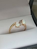 Ring in presentation box showing two opals and central diamond accent