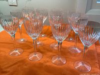 Set of 12 Stuart Crystal wine glasses arranged on orange fabric showing full set with uniform classic cut design.