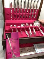 Overview of the 46-piece silverplated cutlery set in the original wooden box with red velvet lining, including knives, forks, spoons, and serving utensils visible.