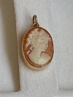 Front view of oval shell cameo pendant showing carved female profile.