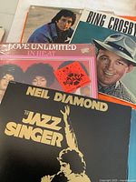 Photo of vinyl record covers showing Neil Diamond's The Jazz Singer and Bing Crosby albums, along with Love Unlimited album.