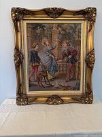 Full view of the framed tapestry depicting an aristocrat scene with three figures and a dog, showing overall condition and frame detail.