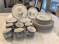 Photo showing full set of stacked plates and cups on counter, arranged by type and size.