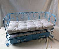 Full view of blue metal doll daybed with tufted mattress and pull-out trundle drawer beneath