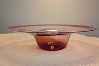 Side view of the large glass bowl showing its wide flared rim and deep reddish base.