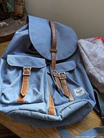 Blue Herschel backpack with two front pockets and leather straps shown closed