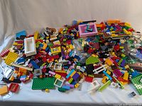 Mixed LEGO bricks and parts loosely spread with various colors and shapes, including some specialty pieces and window frames