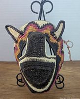 Front view of the brightly colored woven animal mask showing detailed facial weaving and prominent ears.