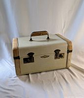 Closed vintage Flite 69 vanity case with leather corner accents and metal handle mounted on top, showing front and latches.