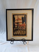 Framed colored woodcut print of a balcony view, showing the full frame, mount, and artwork.