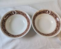 Top view of two white ceramic bowls showing interior design with brown floral patterned rim and Mickey Mouse logos.