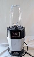 Front view of Ninja Nutripro blender base unit with attached blending container and visible power cord, showing overall condition and details.