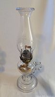 Full view of the vintage finger loop glass oil lamp with original burner marked 'CORRECT', showing finger loop handle and tall chimney.