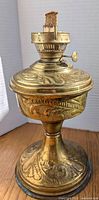 Full view of the brass oil lamp base showing the detailed floral embossing and overall shape.