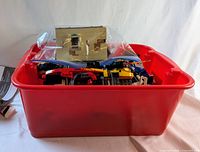 Red plastic bin containing assorted LEGO pieces, packed full with some modules visible.
