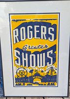 Full view of the framed Rogers Greater Shows poster in yellow and blue with circus/midway theme