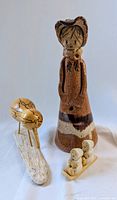 Photo of the handmade clay girl figurine with visible flower holes, spalted birch bird on driftwood base, and two small sledding children figurines.